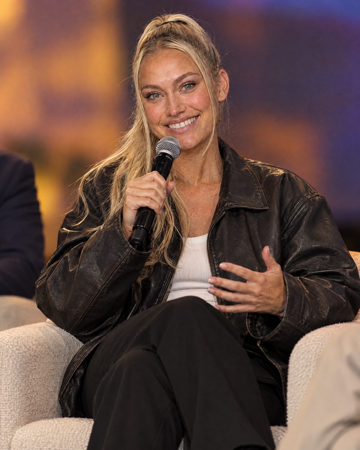 Nina Vellin speaking on a conference panel with a handheld microphone.